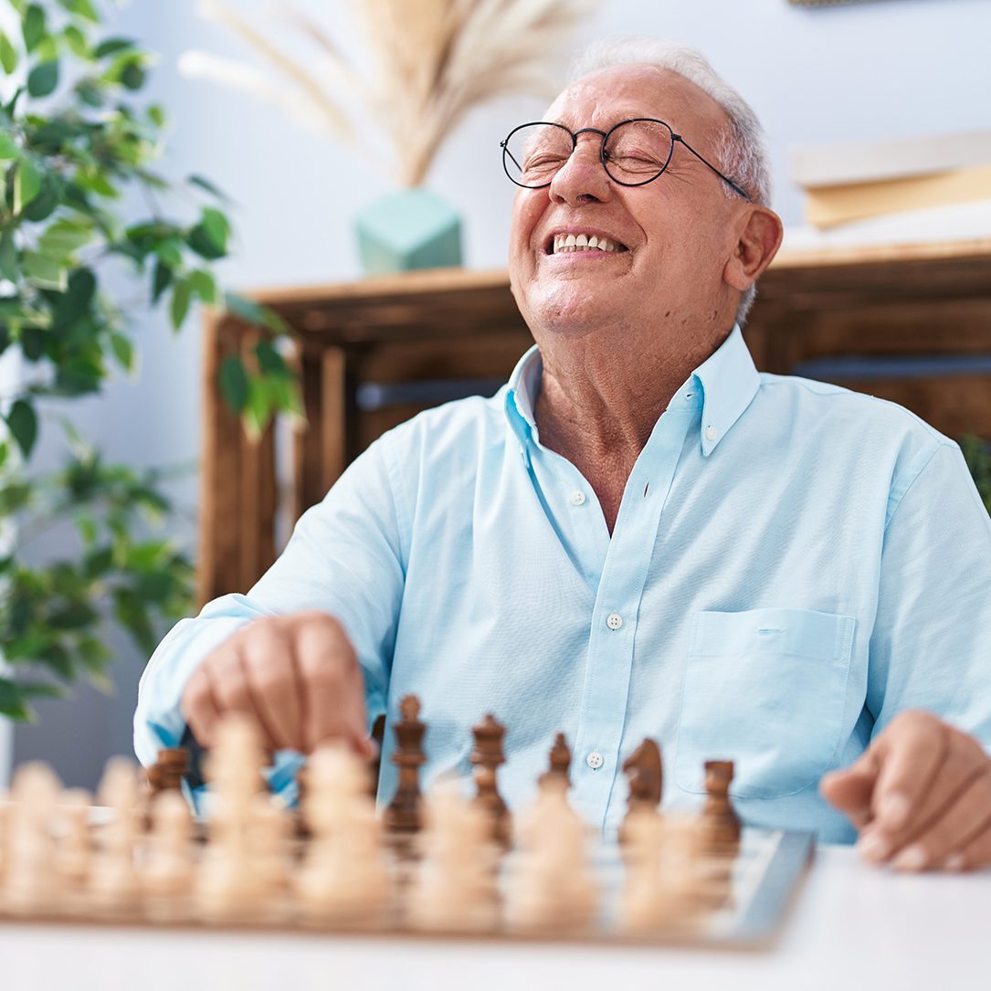 Senior man enjoying a game of chess with companionship aide
